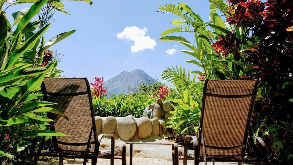 Two chairs are sitting on a patio with a mountain in the background.