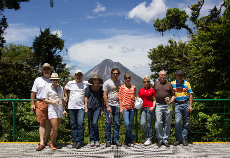 Group of seven people standing on a bridge with a mountain and trees in the background.