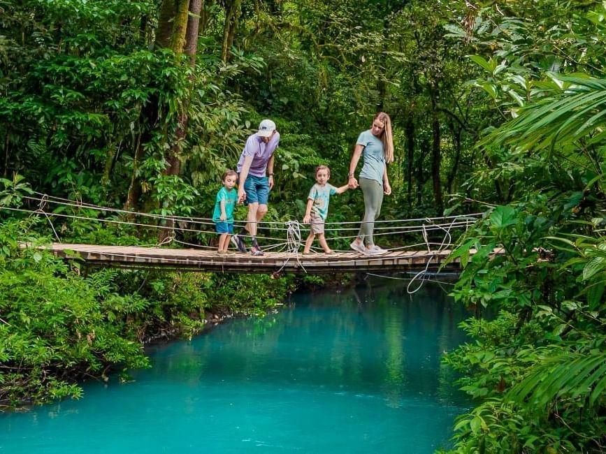 A family is walking across a wooden bridge over a river.