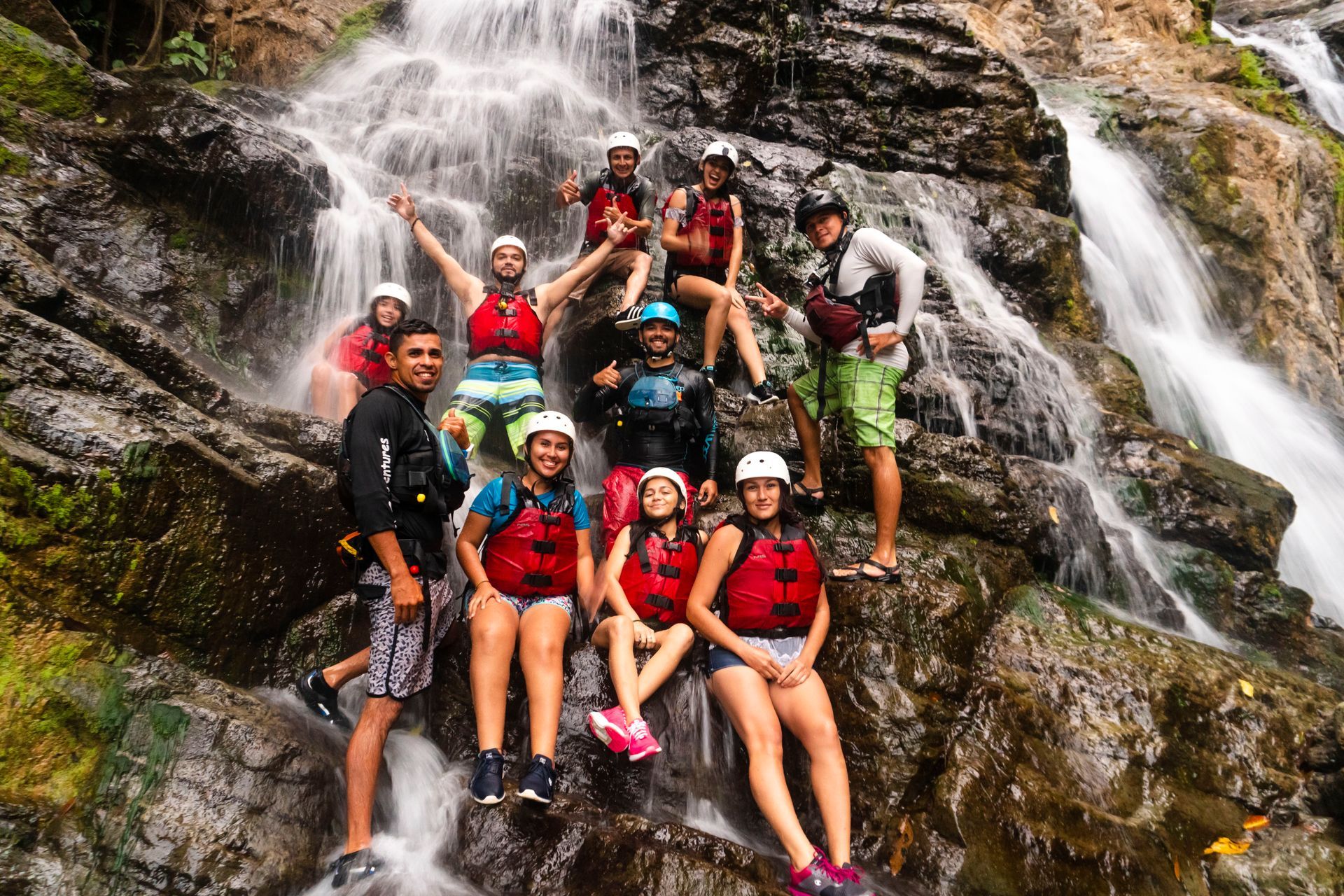 A friends are posing for a picture in front of a waterfall