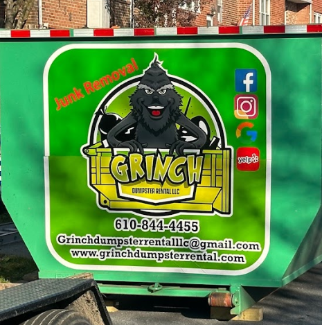 A green dumpster with the word grinch on it