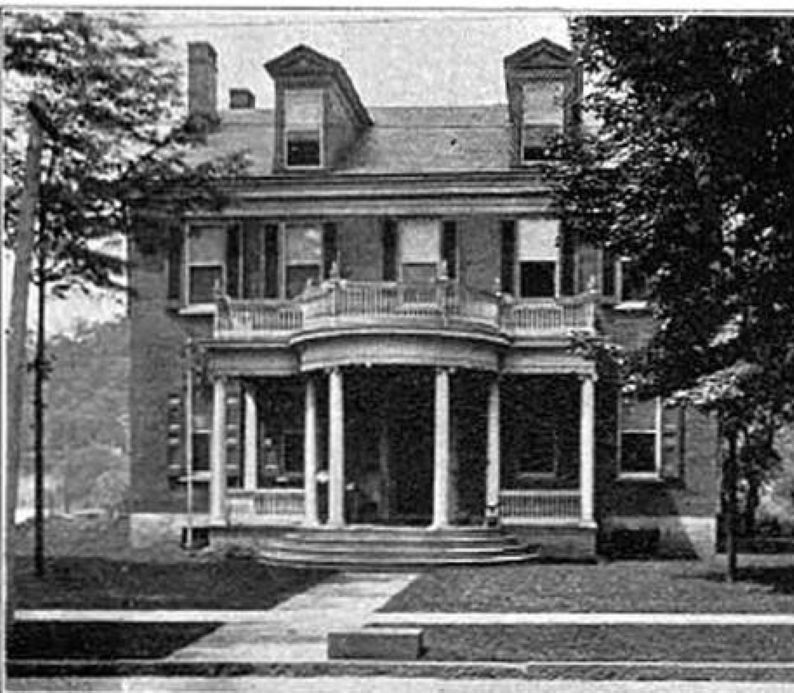 The front door of a house with a porch and plants in front of it.