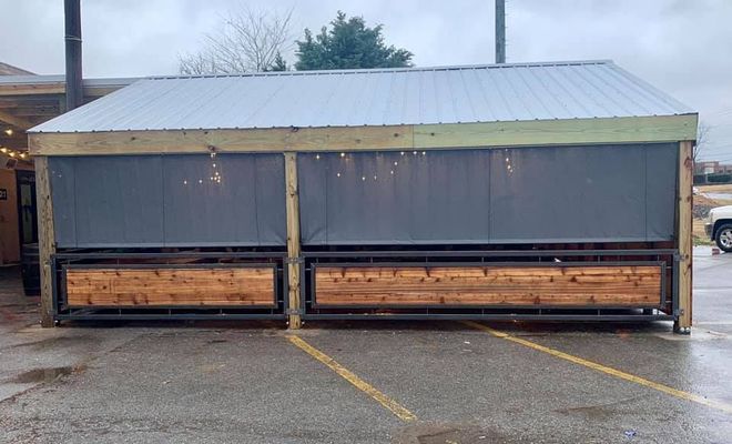 A shed is sitting in a parking lot next to a building.