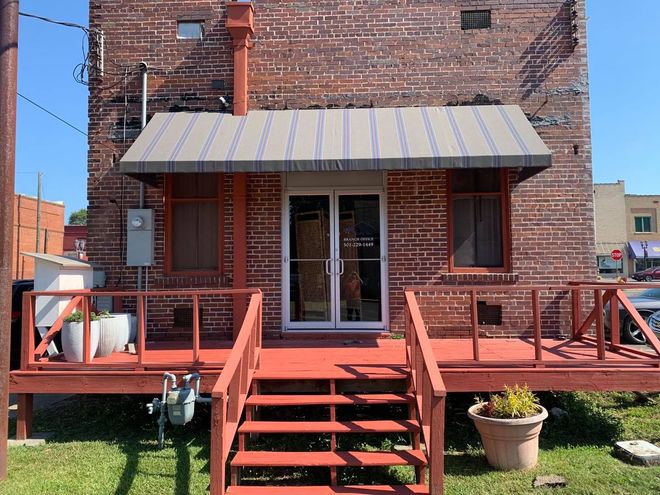 A brick building with a deck and stairs in front of it.