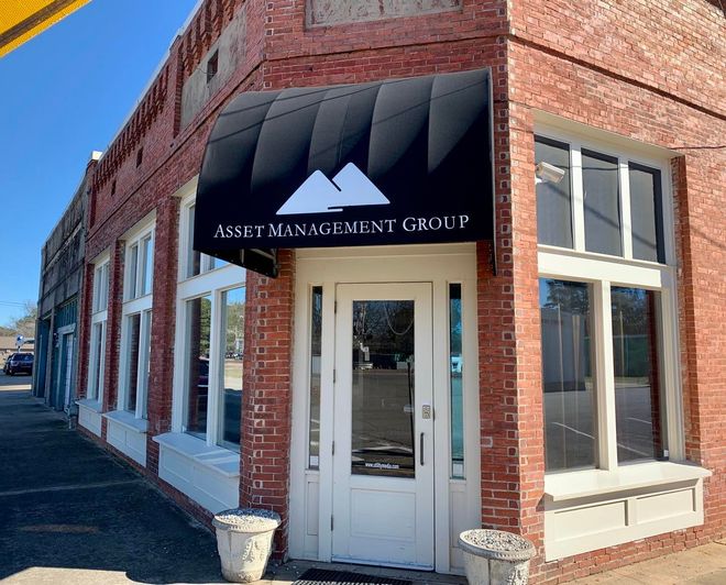 A brick building with a black awning that says asset management group