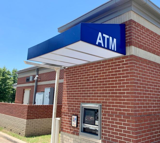 A brick building with a blue sign that says atm