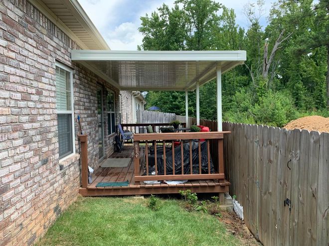 A brick house with a wooden deck and a covered porch.