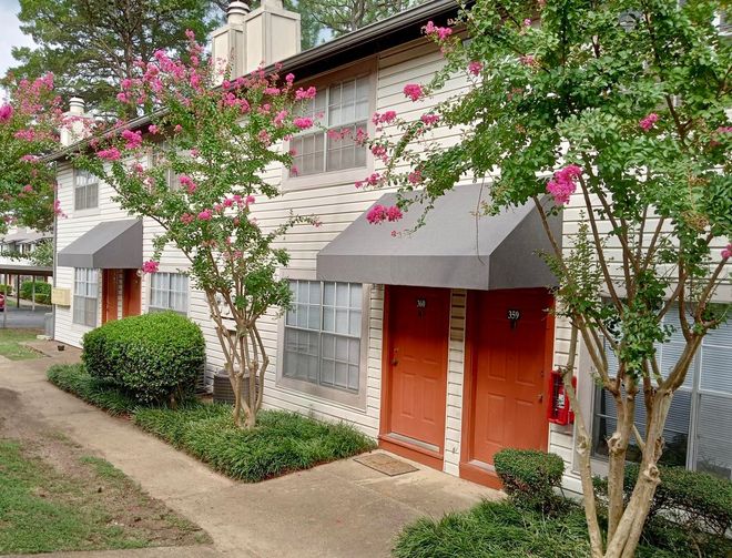 A row of apartment buildings with trees in front of them