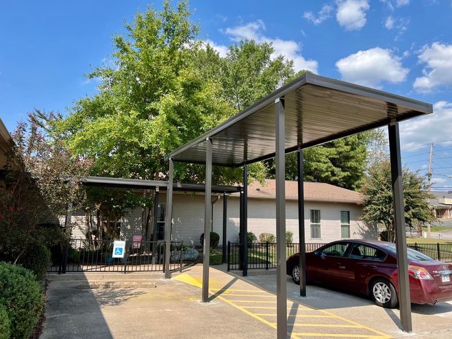 A car is parked under a canopy in a parking lot.