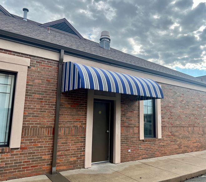 A brick building with a blue and white striped awning over the door