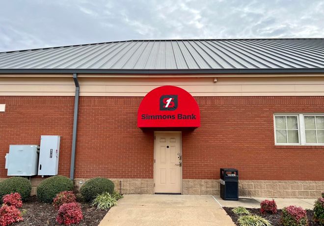 A brick building with a red awning over the door.