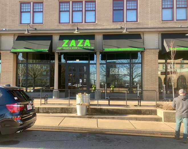 A man standing in front of a zaza restaurant