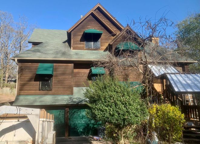 A large wooden house with green awnings on the windows