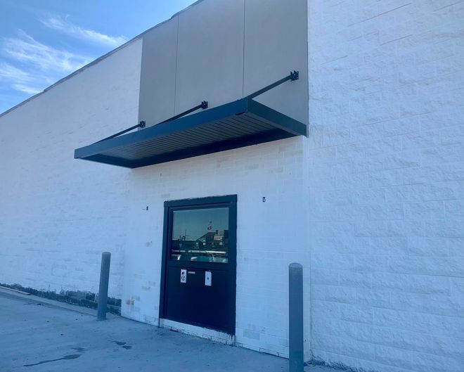 A white building with a black door and a canopy over it.