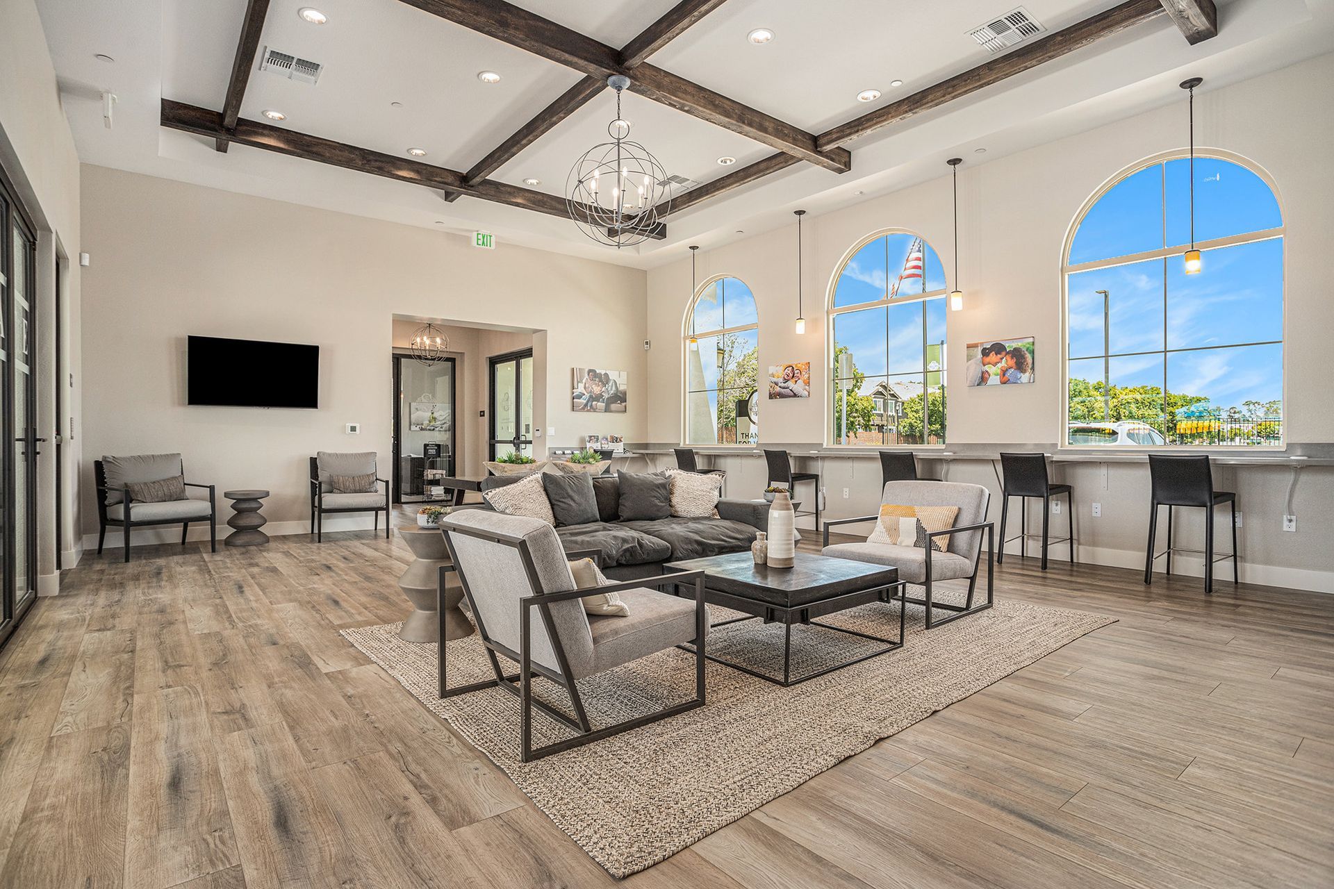 Spacious resident lounge with grey seating, a wall-mounted TV, and arched windows. View available homes at The Silvergate.