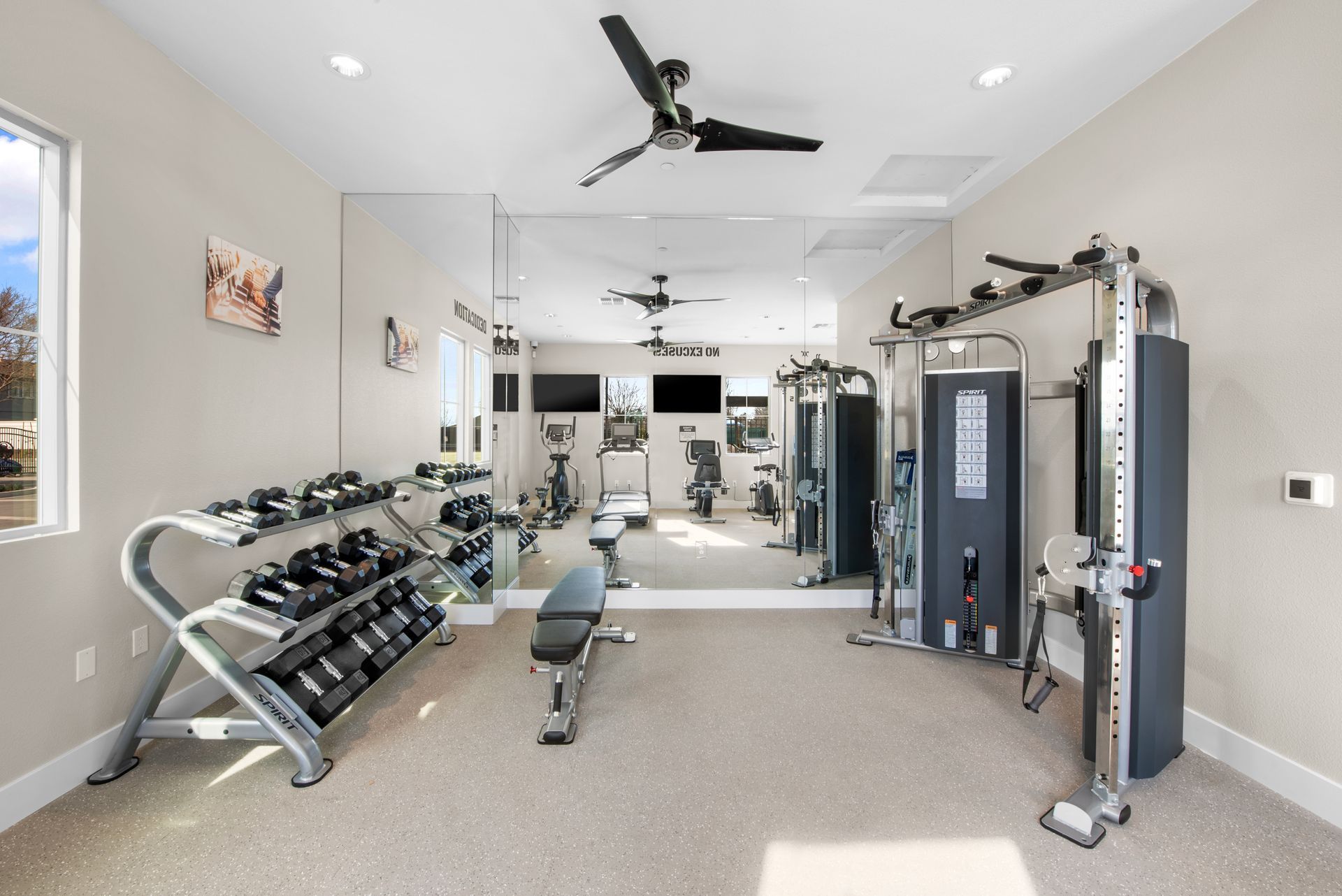 Bright fitness center with free weights, cardio machines, and mirrored wall. Experience Brentwood living at Silvergate.