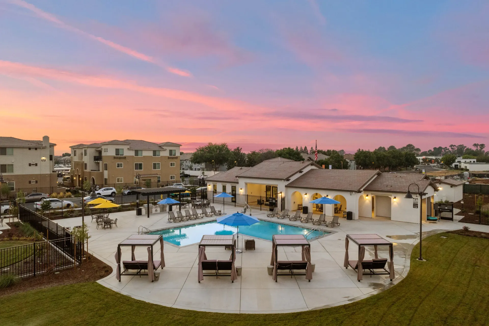 Outdoor apartment community pool area with lounge chairs and cabanas at sunset. Picture yourself at The Silvergate.