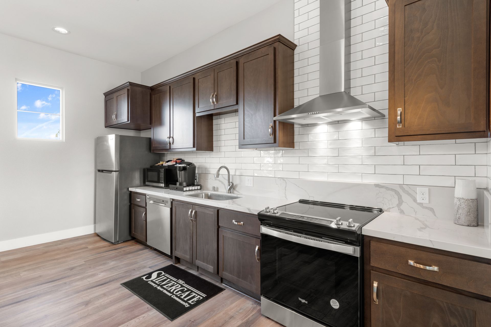 Modern apartment kitchen with dark wood cabinets, stainless appliances, and white subway tile backsplash. Step into relaxed living at The Silvergate.