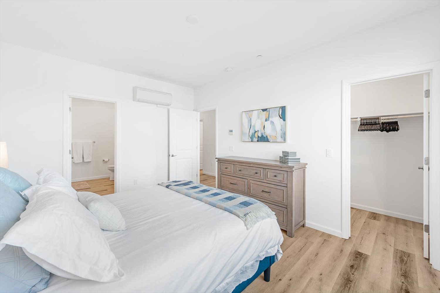 Bright bedroom with white walls, large bed, dresser, and open closet. Discover what makes Silvergate feel like home.