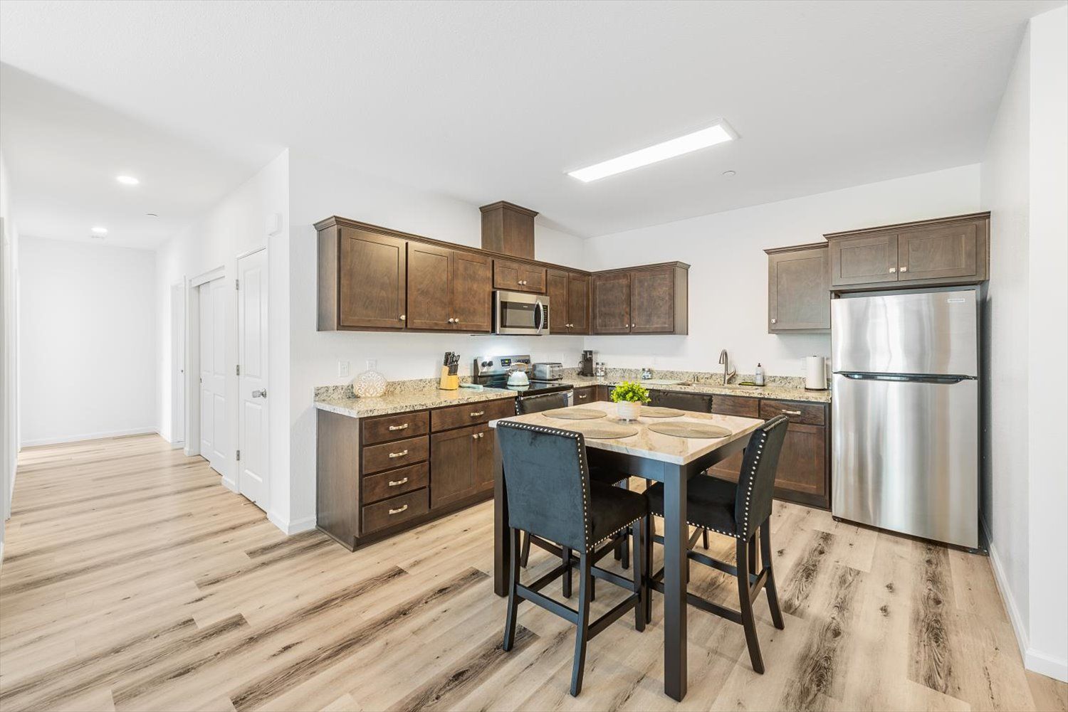 Kitchen with dark wood cabinets, granite countertops, stainless steel appliances, and an island with seating.