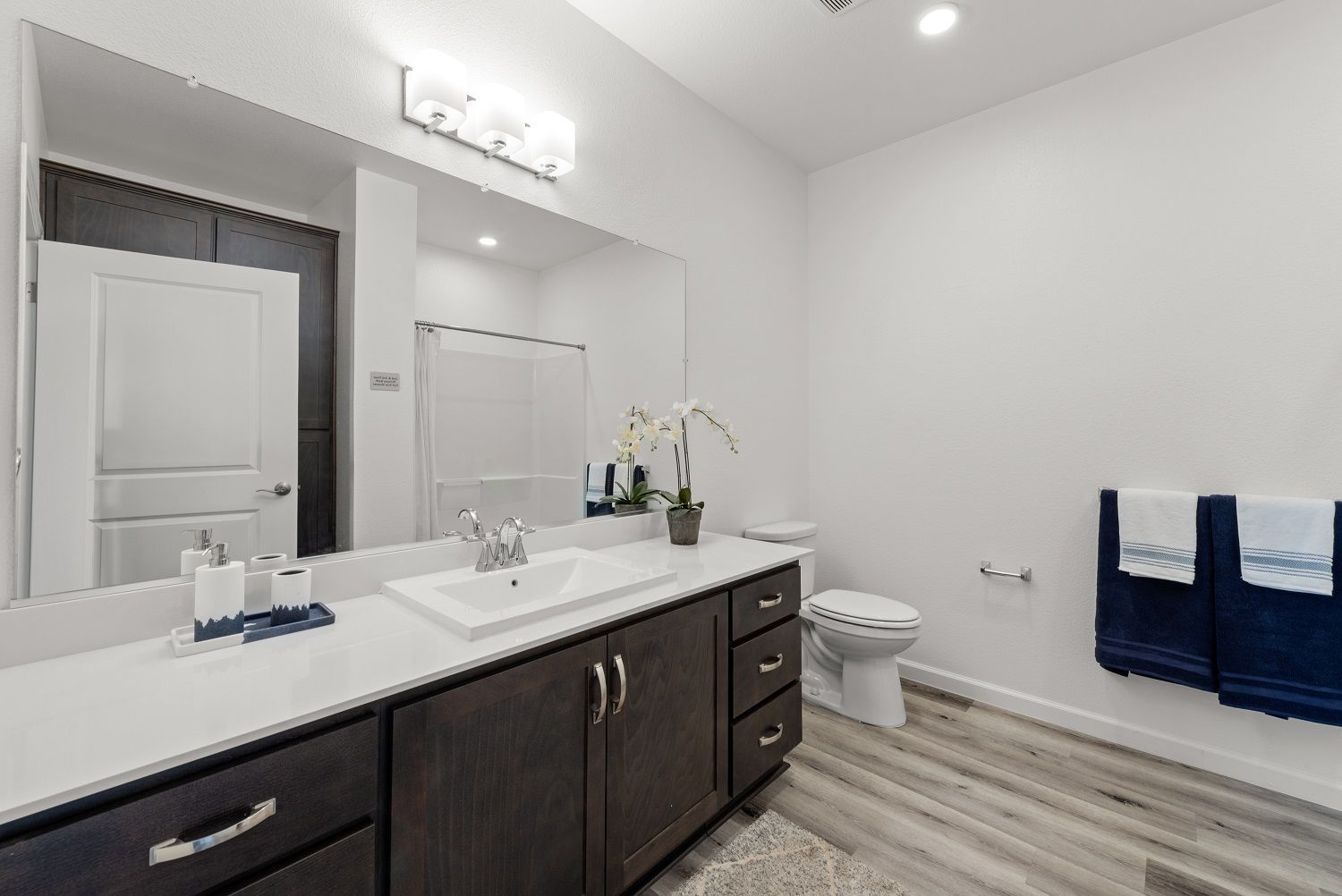 Modern bathroom with double-sink vanity, large mirror, and toilet. Discover a welcoming place to call home at The Silvergate in Brentwood, CA.