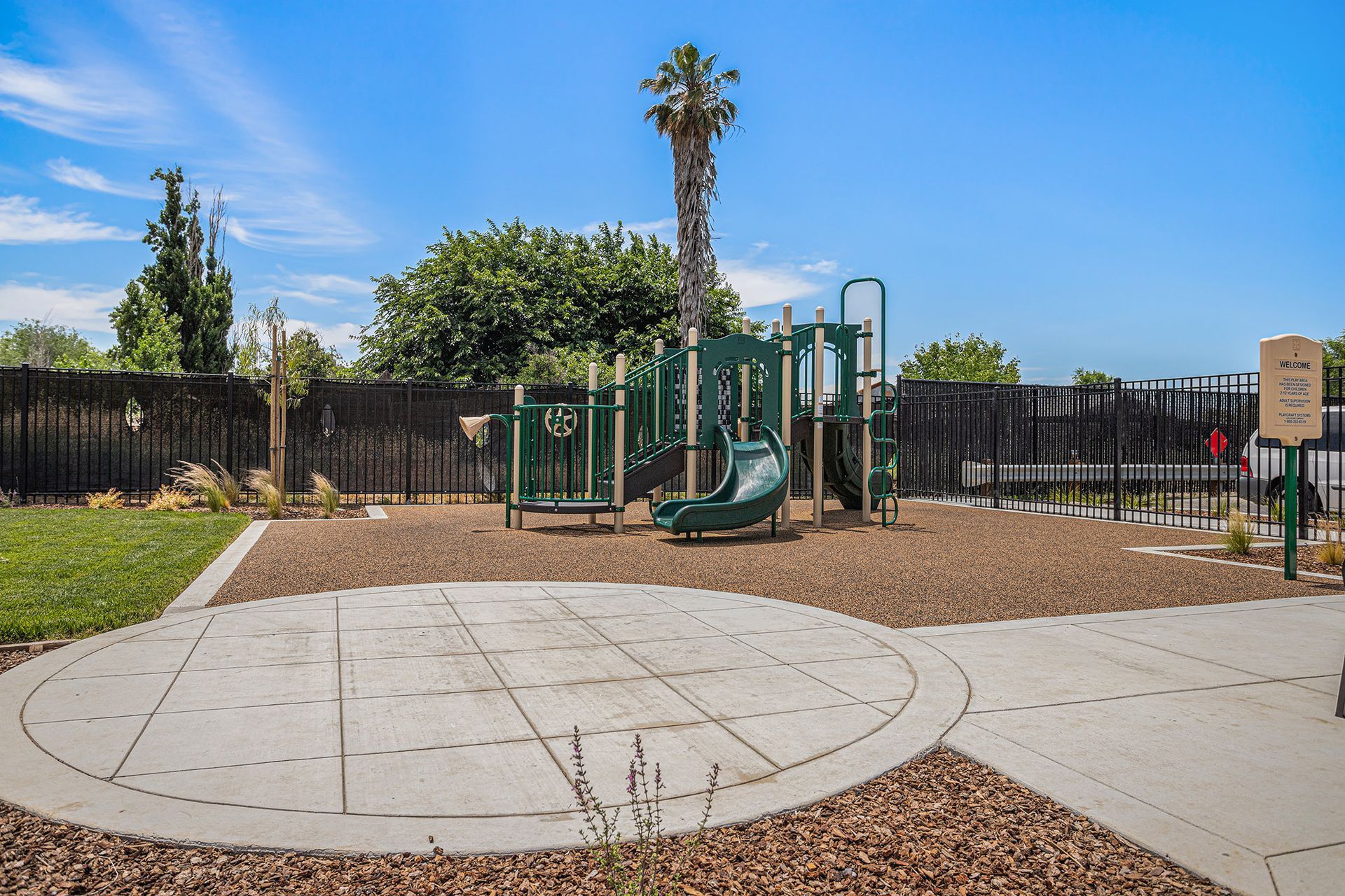 Community playground with a green play structure and slide, fenced in. Get to know The Silvergate community.