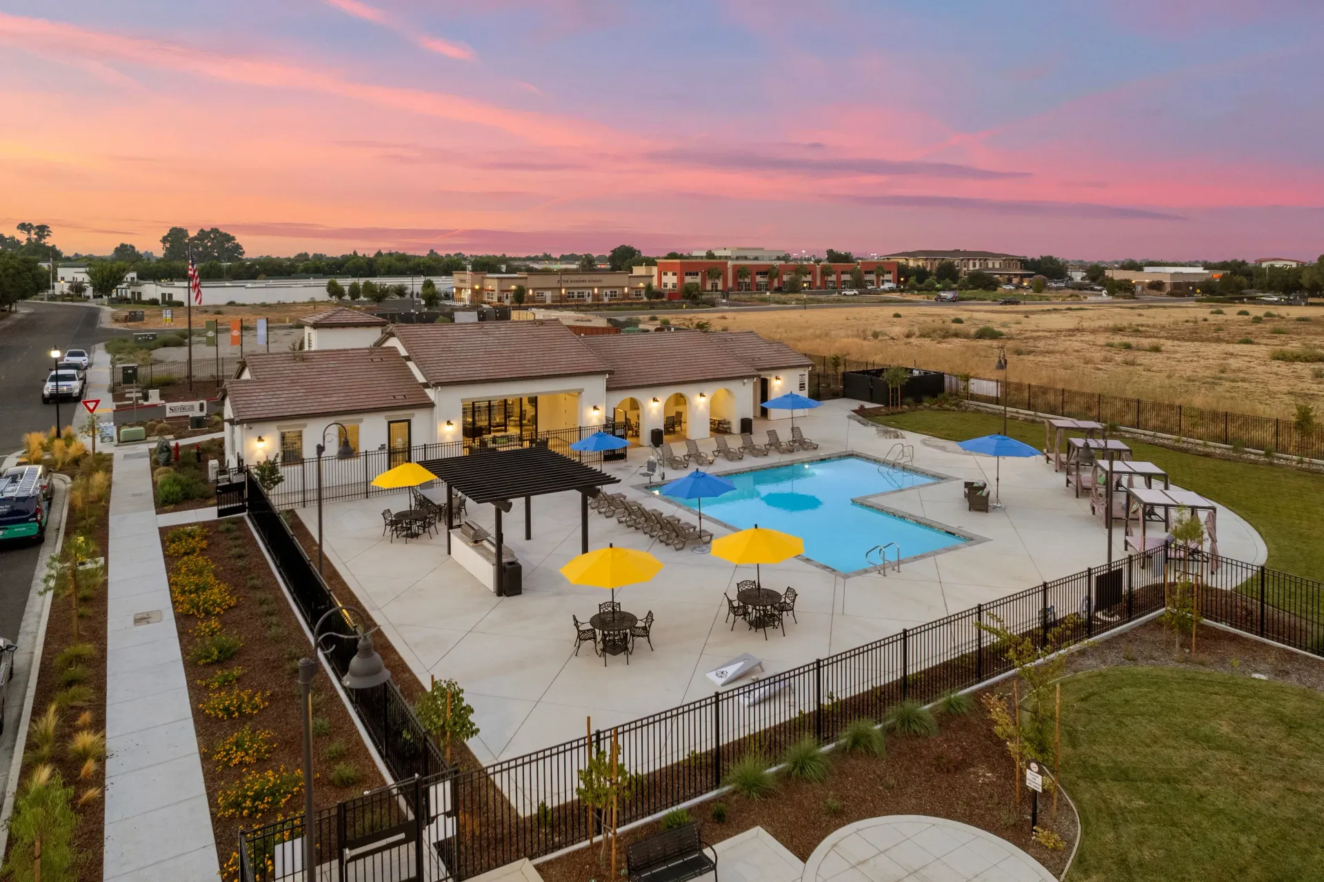 Aerial view of a communal apartment pool with lounge chairs and umbrellas. Discover your next home at The Silvergate.