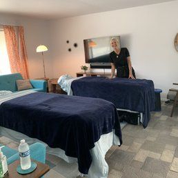 A woman is standing next to two massage tables in a room.
