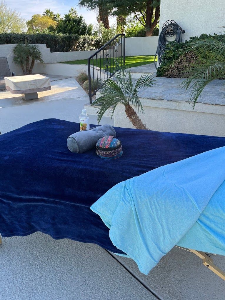 A massage table with a blue towel and a bottle of hand sanitizer on it