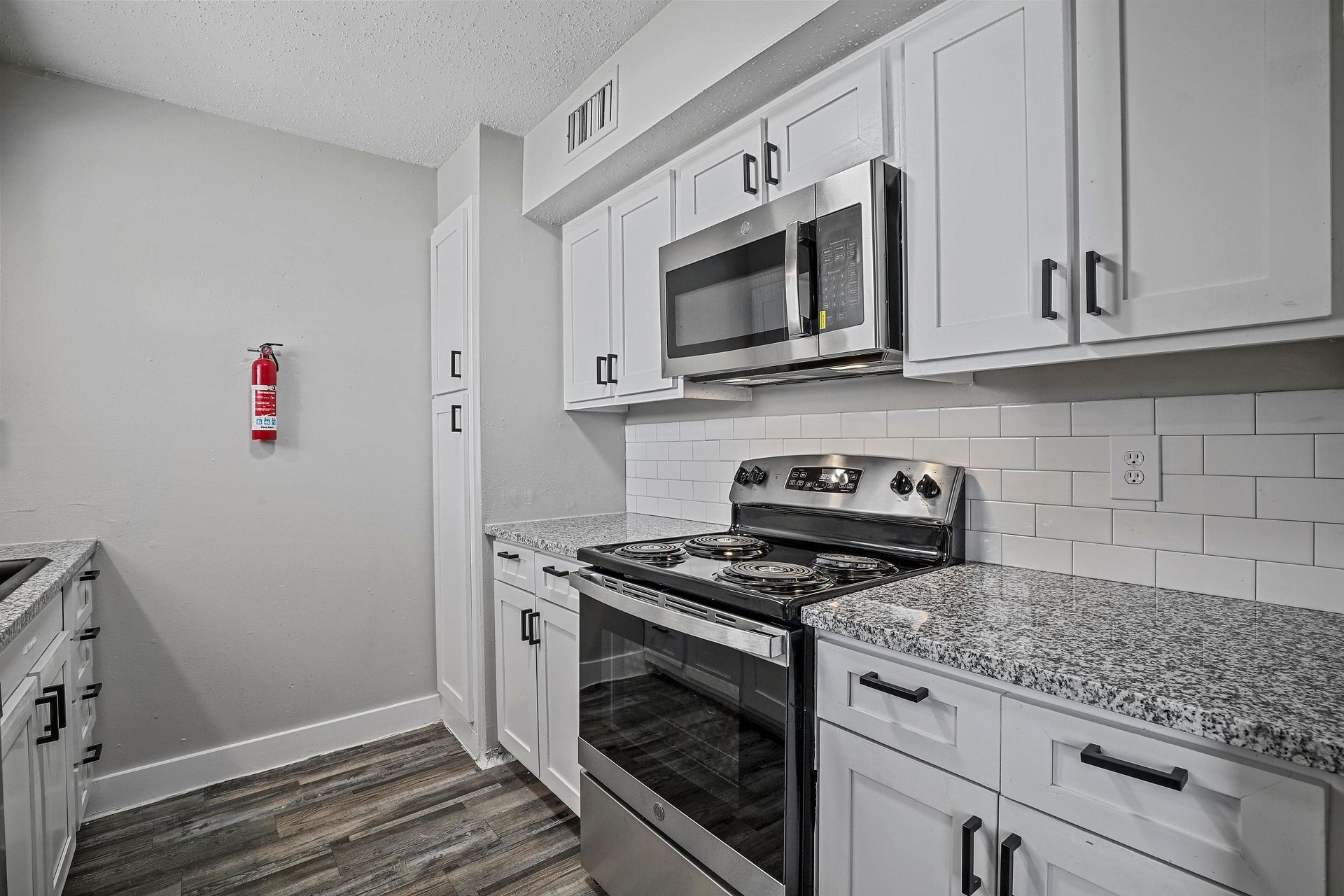 Modern kitchen with white cabinets, stainless steel appliances, and gray countertops.