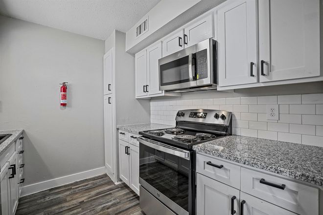 Modern kitchen with white cabinets, stainless steel appliances, and gray countertops.