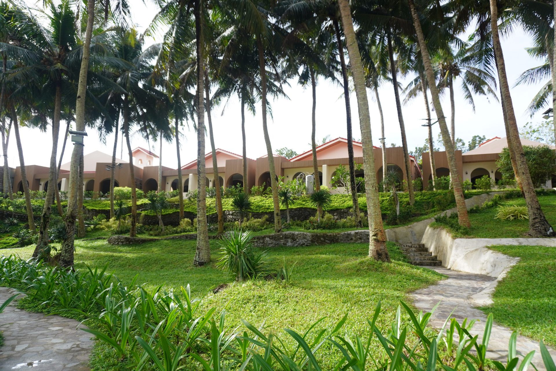 Tropical garden with palm trees, green lawns, and villas in the background