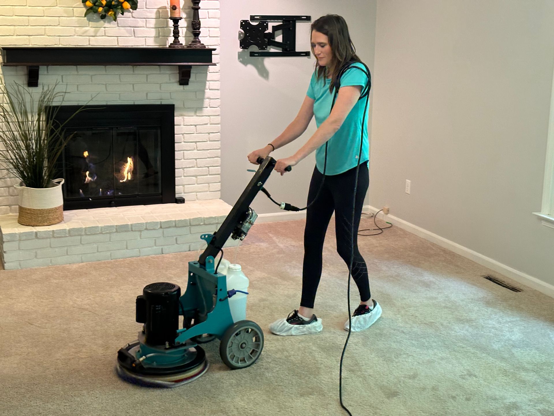 A woman is using a machine to clean a carpet in a living room.
