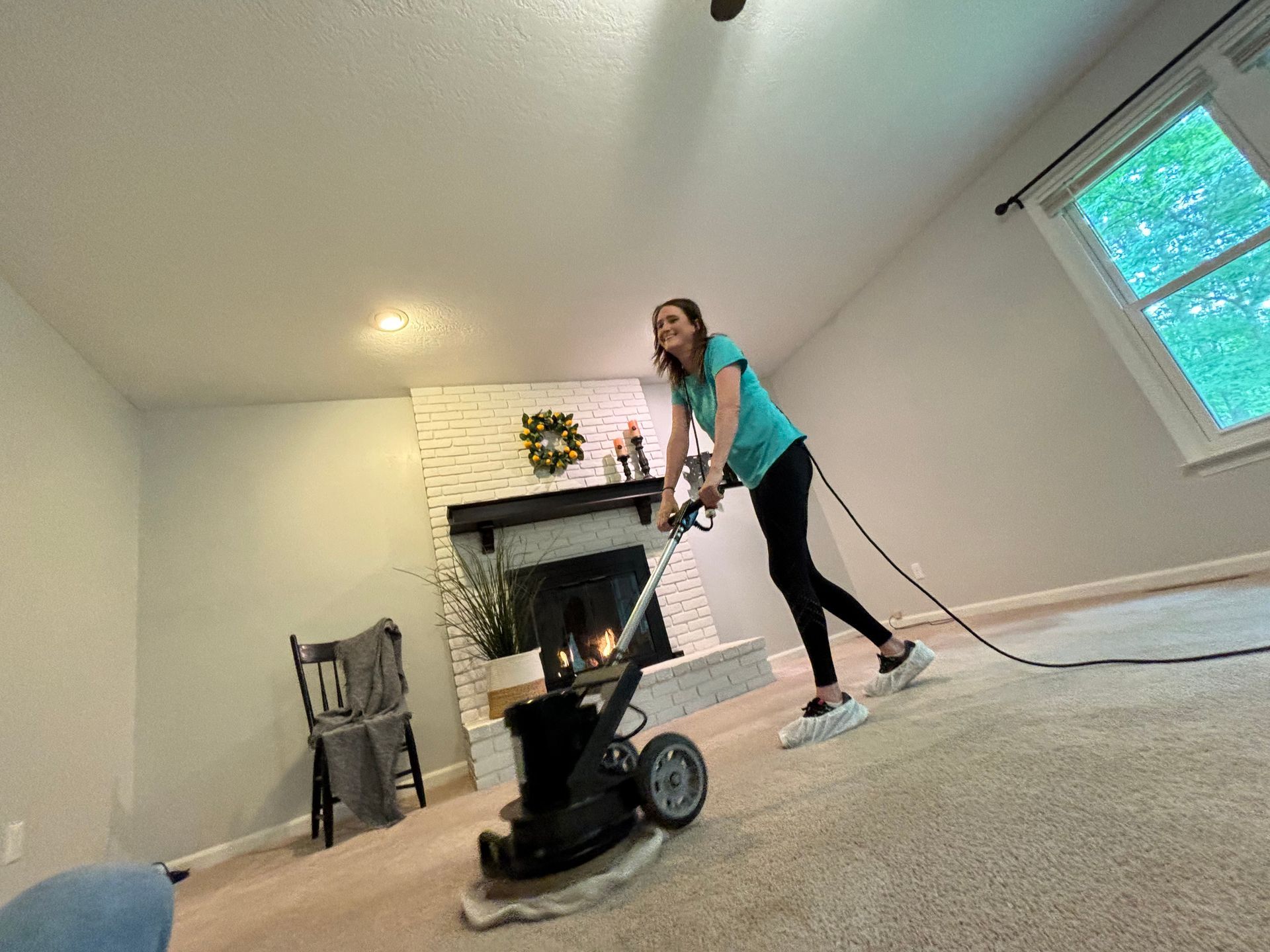 A woman is using a machine to clean a carpet in a living room.