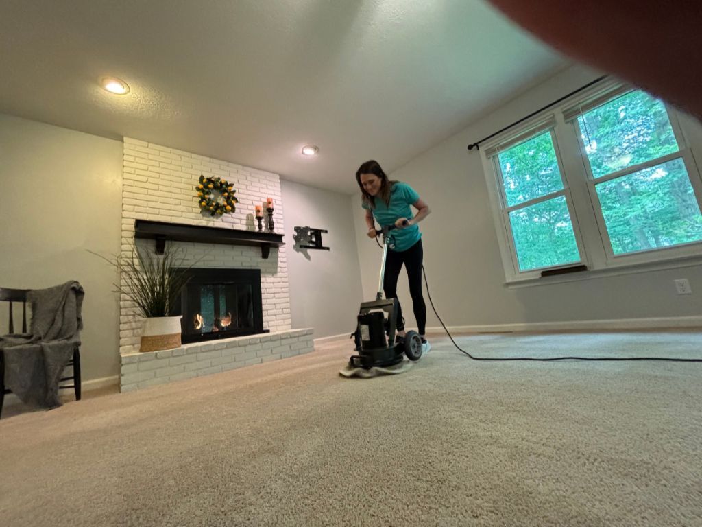 A woman is using a vacuum cleaner to clean a carpet in a living room.