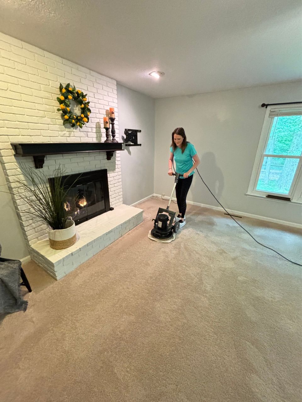A woman is using a vacuum cleaner to clean a carpet in a living room.