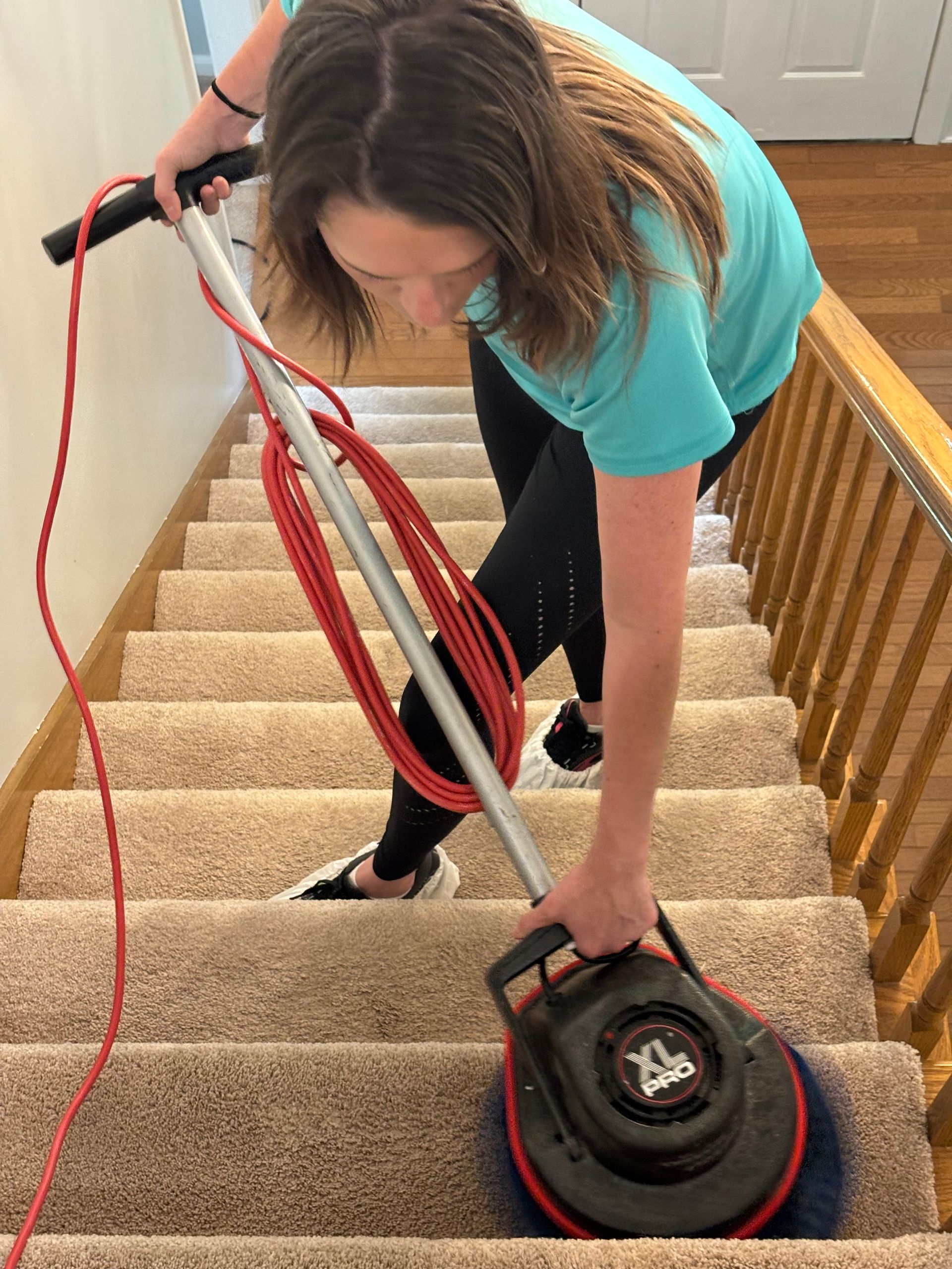 A woman is cleaning the stairs with a vacuum cleaner.