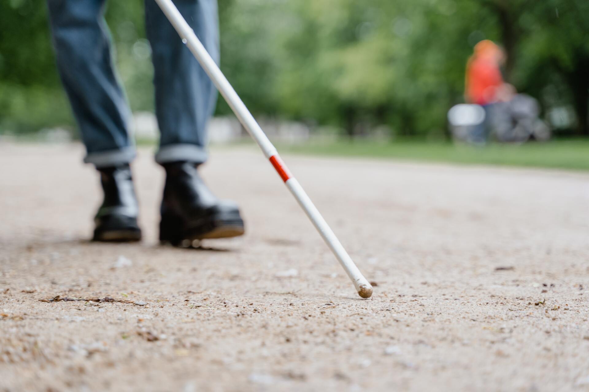 Photo of a person's feet walking with a white and red cane ahead of them