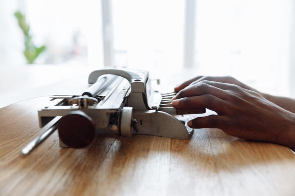 Photo of an African American person putting their hands on the keys of a vintage brailler