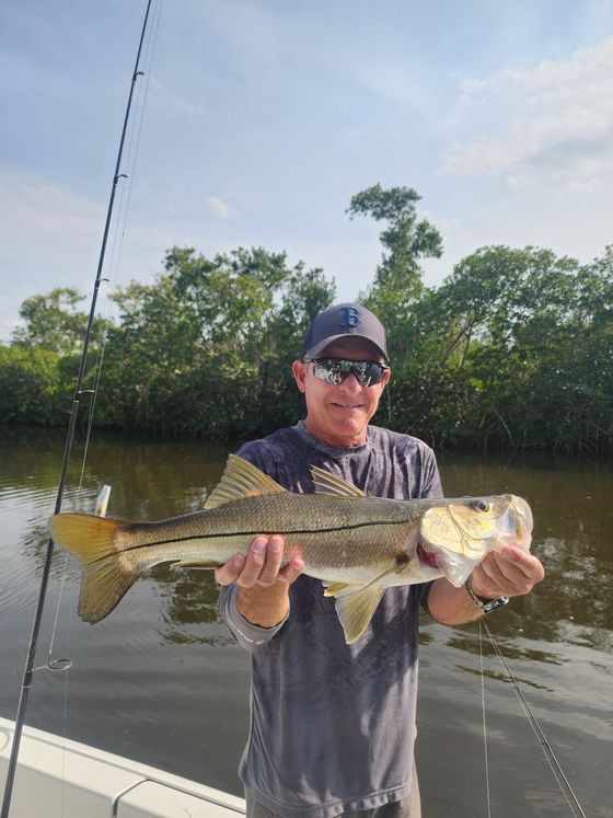 A man is holding a large fish in his hands on a boat.