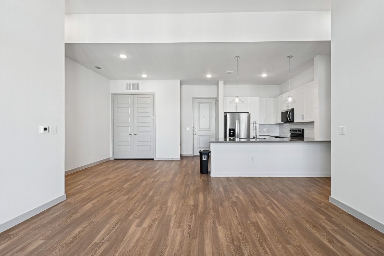 Open-concept living area with kitchen island, stainless appliances, and light wood flooring.