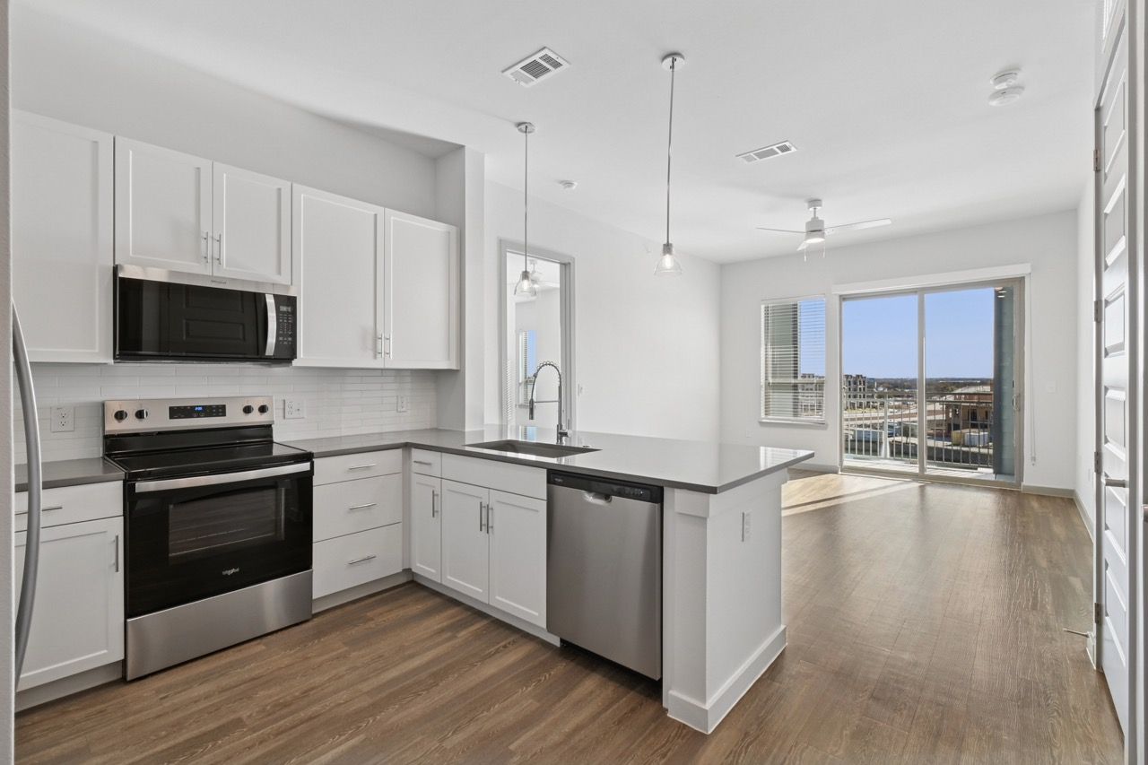 Modern kitchen with white cabinets, stainless steel appliances, and an island in an apartment.