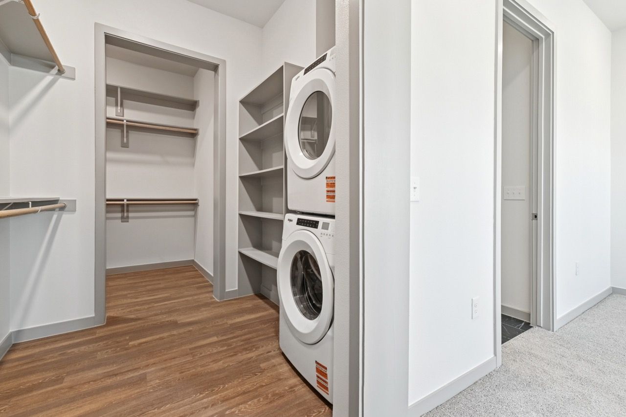 Laundry closet with stacked washer and dryer and built-in shelves.