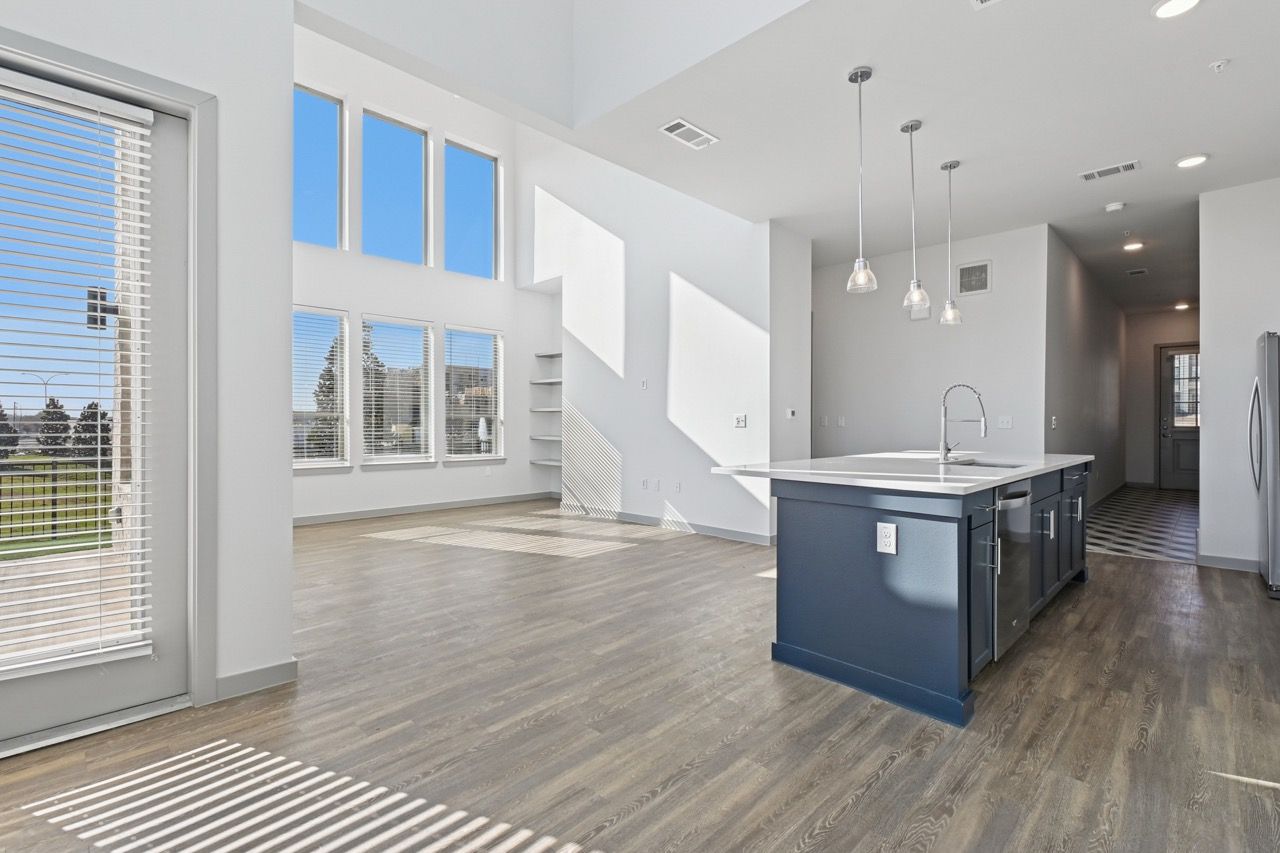 Open-concept kitchen with blue island, pendant lights, and large windows.