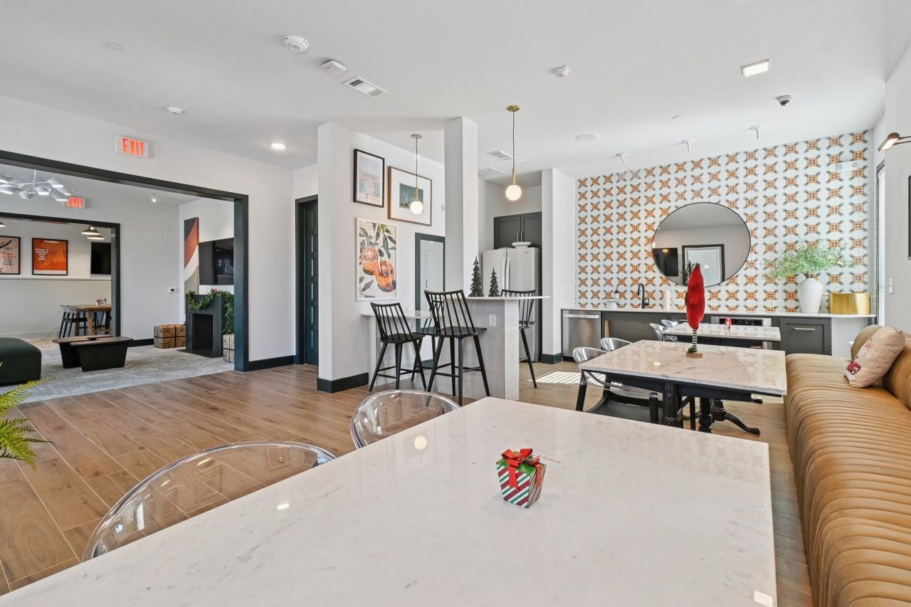Modern community lounge with marble-top tables, bar seating, and decorative wallpaper.