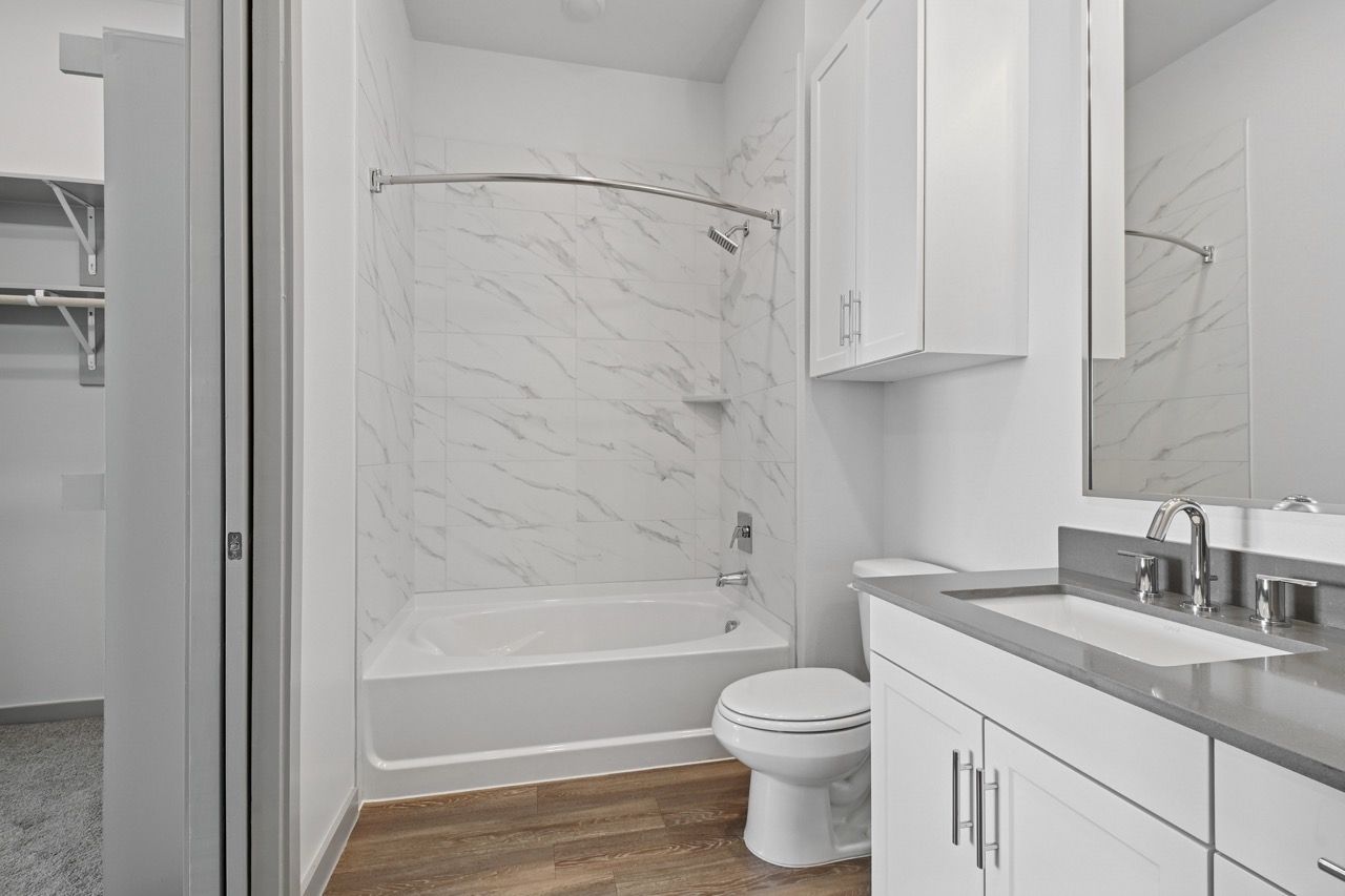 White bathroom with tub/shower, toilet, and vanity.