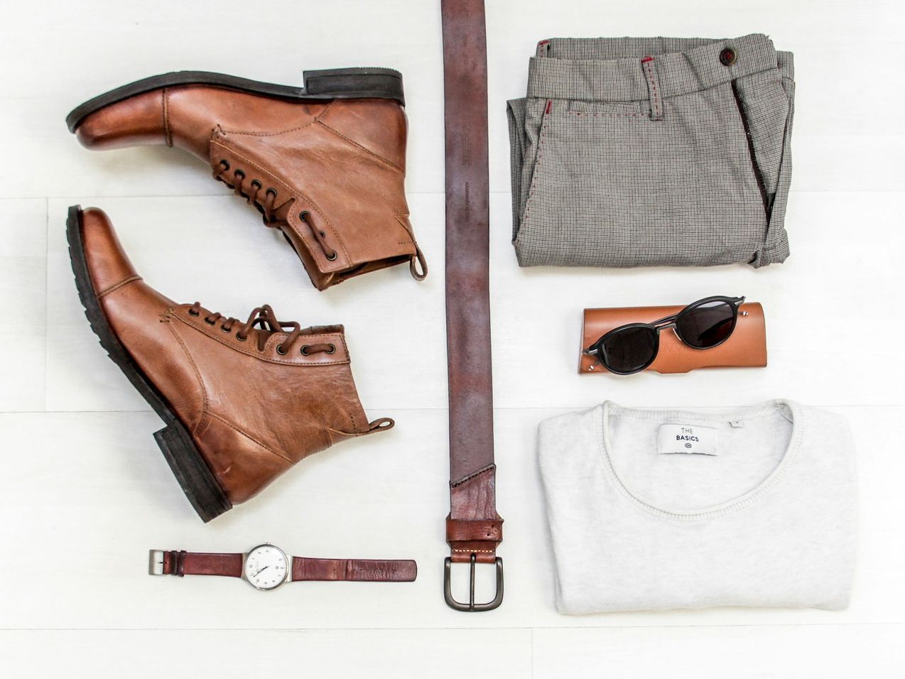 Image of a collection of clothing and accessories including pants, shirt, belt, shoes, sunglasses and wrist watch