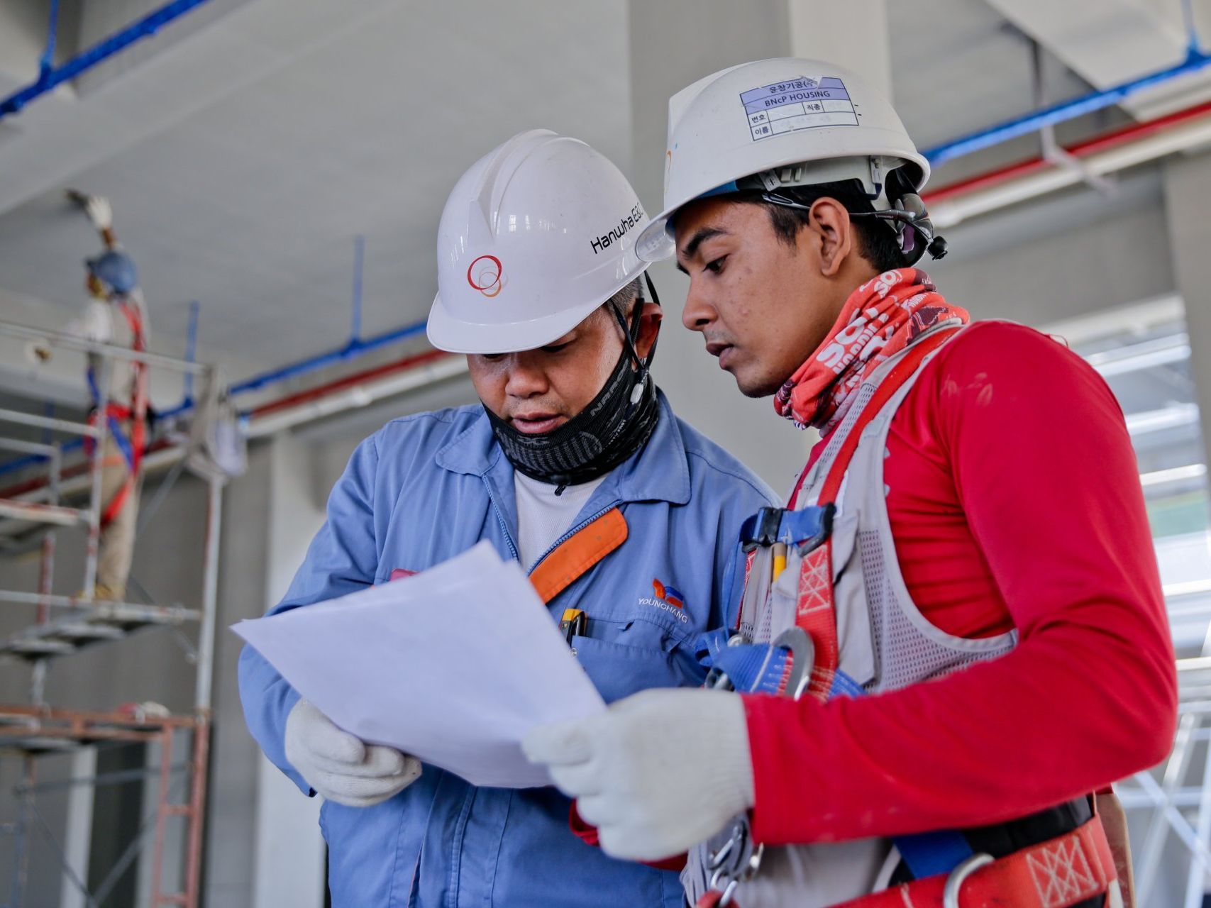 Two construction workers are looking at a piece of paper.