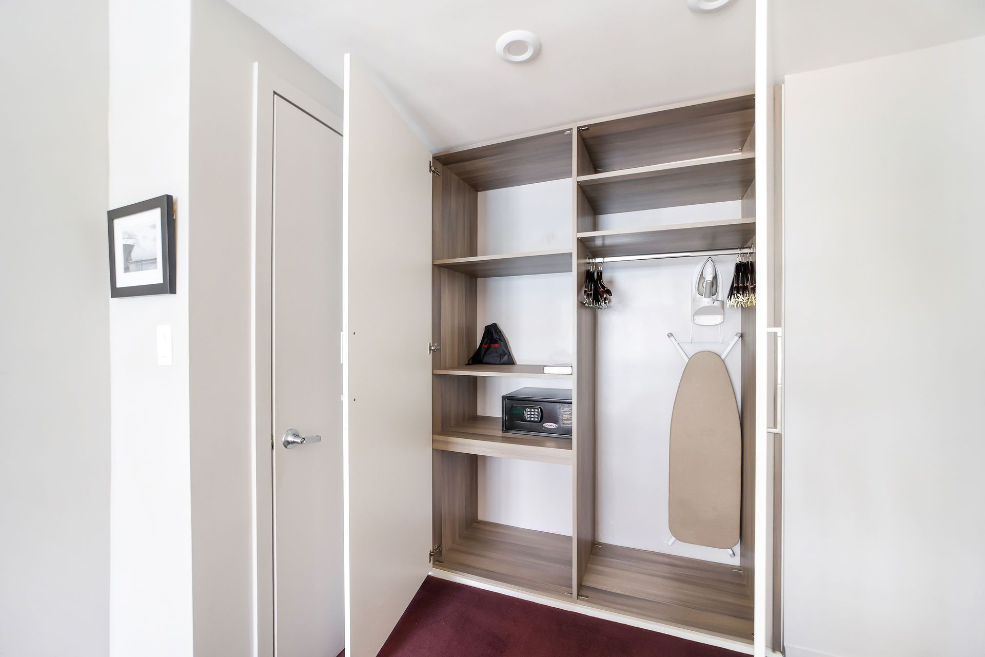 Open closet with shelving, a hanging rod, and an ironing board.