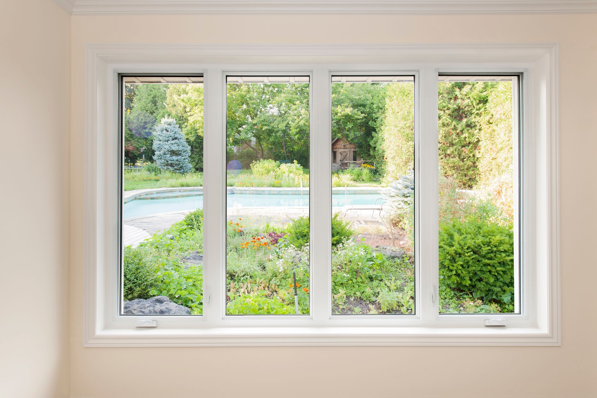 A white four-pane window frame looking out onto a backyard garden with a swimming pool and lush greenery.